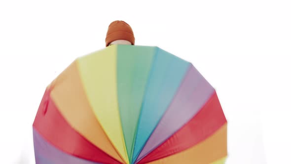 Charming Caucasian Man Shows Multicoloured Umbrella to the Camera and Spins It White Background