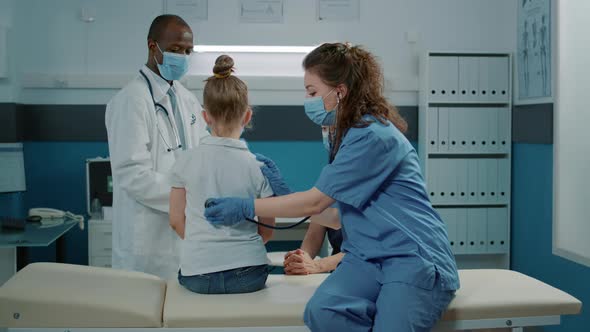 Medical Assistant Consulting Child with Stethoscope in Cabinet