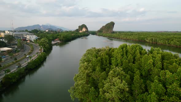 aerial drone flying low over an island forest surrounded by a river and limestone mountains (Khao Kh