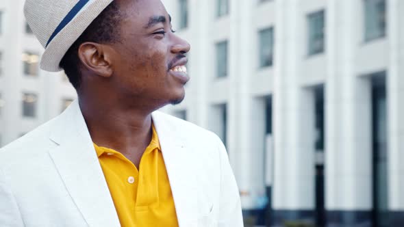 African American man in white classic suit looks around with cheerful