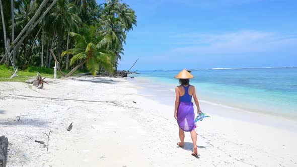 Slow motion: woman holding snorkeling gear walking on sunny tropical beach caribbean sea palm trees