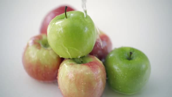 SLOMO of Water Poured on Apples on White Backdrop