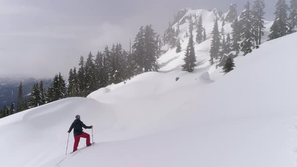 Aerial Of Man Snowshoeing To Summit On Mountain Ridge With Fresh Deep Powder alt