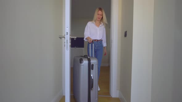 a woman enters the room with a suitcase and lies down on the bed.