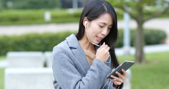 Woman talking on mobile phone with earphone at outdoor