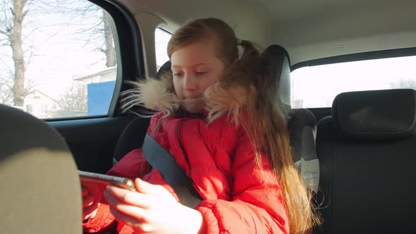 Child Girl In Car With Phone alt