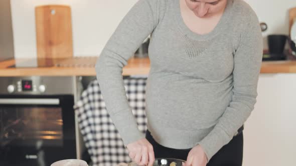 Pregnant woman baking chocolate cake at home