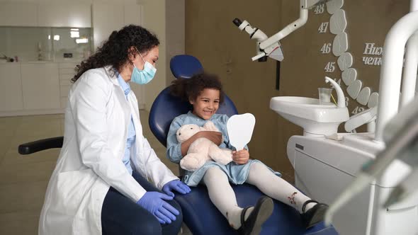 Curly Mixed Race Girl Patient Looking at Teeth