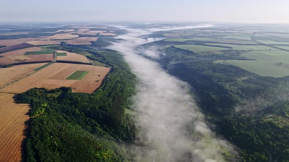 Aerial Drone View of Valley with Village Between Mountains During Misty Morning