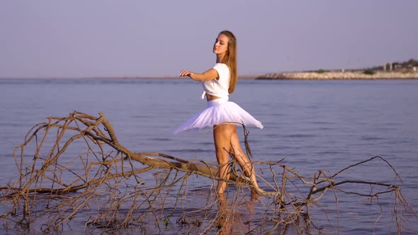 Woman in Tutu and T-shirt Dances Ballet Near Branch in Water