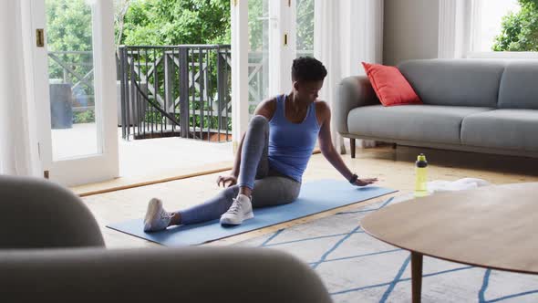 African american woman performing stretching exercise at home