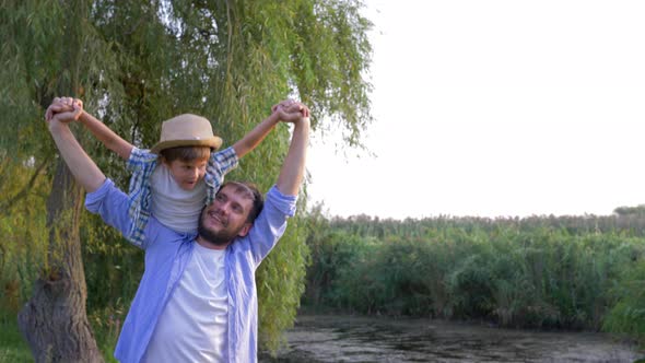 Father Carries Son on Shoulder and Imagines That They Fly Like an Airplane on Family Vacation in