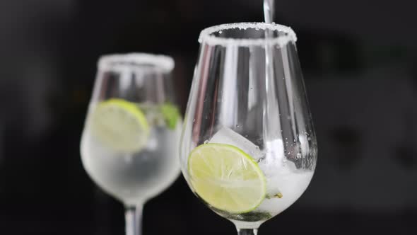 Champagne Wine Poured Into Glass with Ice Lime Slice in Bar