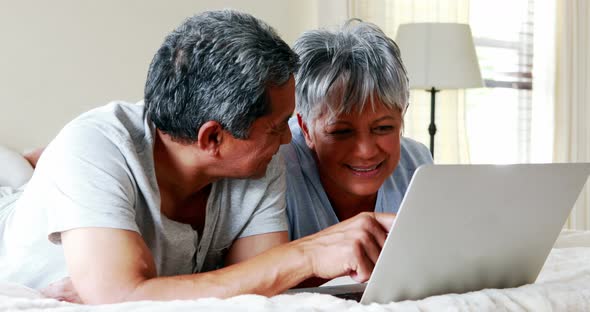 Senior couple using laptop in bedroom 4k