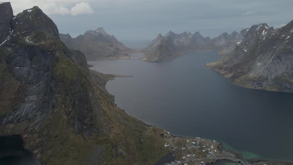 Aerial view overlooking a boat driving on a mountainous fjord, dark, gloomy fall day in Lofoten, Nor