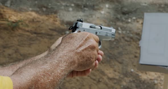 Slow motion of a hand gun firing in a firing range with cartridge flying away