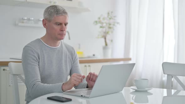 Serious Senior Old Man with Laptop Looking at the Camera 