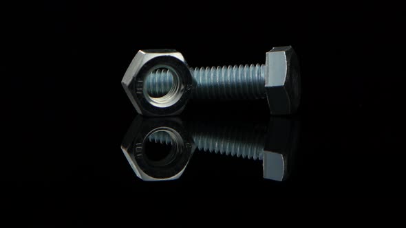 Bolt and Nut Lie Beside and Rotate on Black Stand alt