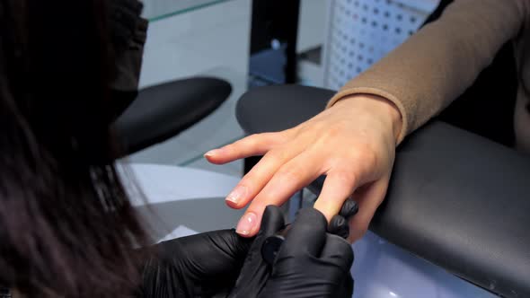 Beautician Applies Coloured Gel on Young Woman Fingernails