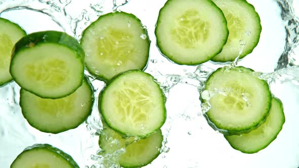 Super Slow Motion Shot of Cucumber Slices Falling Into Water on White Background at 1000Fps