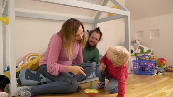 Family playing with spinning toy in children room during the morning.