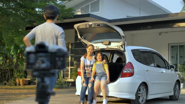 Happy family sit on the car and take a photo together