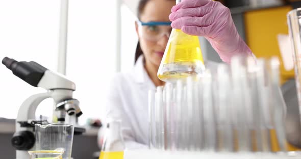 Scientist Holding Flask with Yellow Liquid in Laboratory Closeup