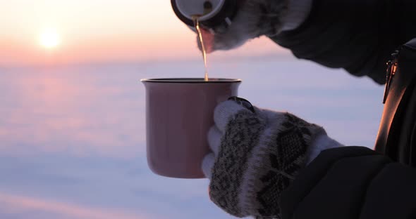 Pours Tea From a Thermos Into a Cup on a Snowy Day