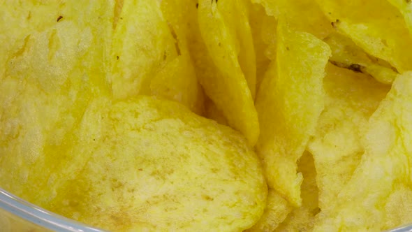 Macro shot potato chips pile into transparent glass bowl, Close up view in 4k.