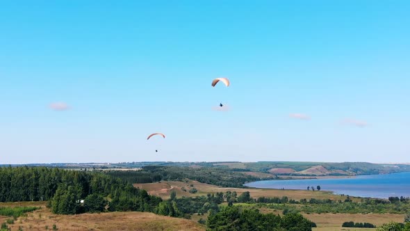 People Are Flying with Ram-air Parachutes Above the Ground