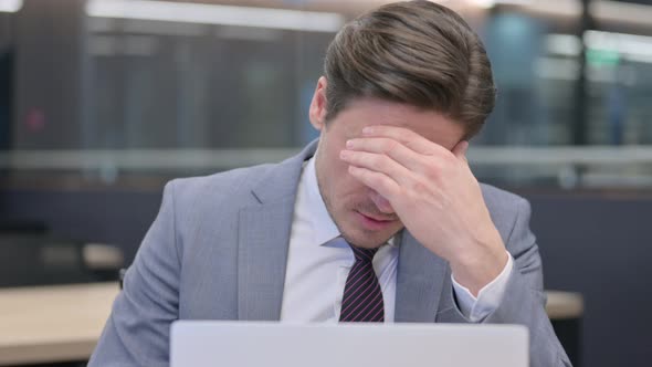 Close Up of Middle Aged Businessman with Laptop having Headache 