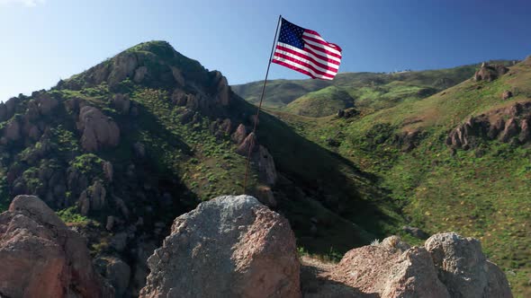 The Flag of the United States of America on Flagpole with Blue Sky on Background