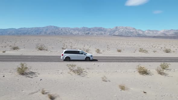 White minivan car driving along empty desert road at Death Valley, California