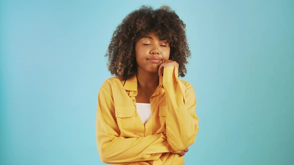 Darkskinned Lady Yawning Covering Mouth By Palm Looking Bored or Sleepy While Posing Against Blue