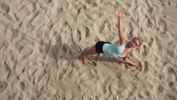 Overhead shot of a young attractive woman doing yoga on the beach