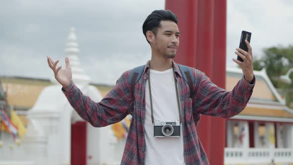 Asian man solo tourists standing using smartphones video chat with friends.