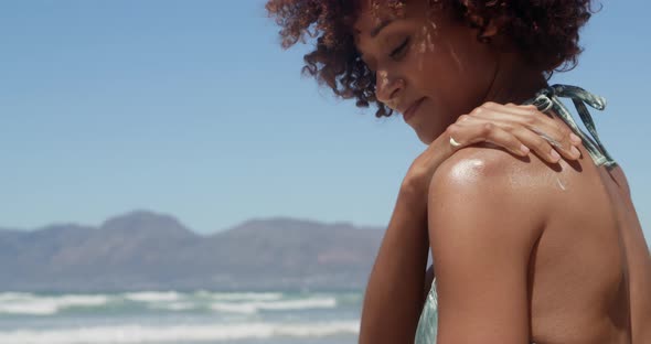 Woman applying sunscreen on shoulders at beach in the sunshine 4k