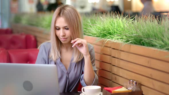 Medium Shot Portrait of Pretty Smiling Businesswoman Working at Cafe Using Laptop