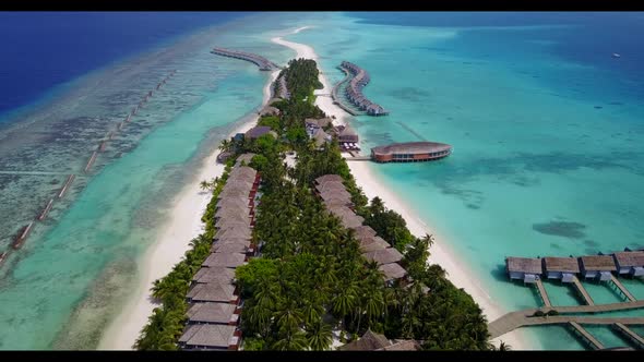 Aerial flying over landscape of tropical tourist beach holiday by transparent lagoon with white sand