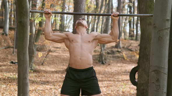 Strong Naked Guy Pulls Up On Pole. Exercise Emphasizes All The Muscles Of The Man.