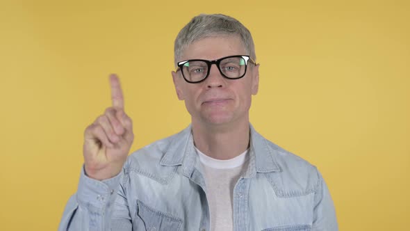 Casual Senior Man Waving Finger To Refuse on Yellow Background
