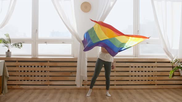 Female Holding LGBT Gay Flag in Hands and Waving on Sunset in Sunny Rays