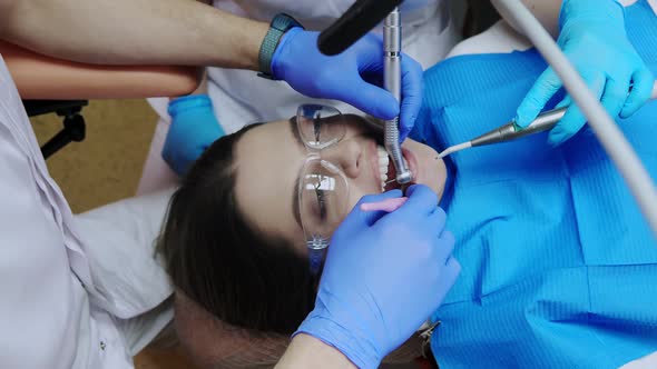 Dentist with assistant under microscope treats the patient's teeth. Modern progressive dentistry.