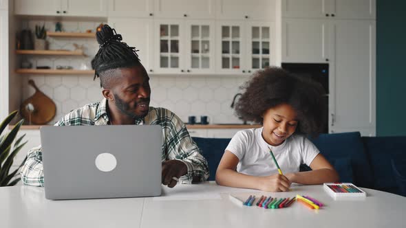 Young African American Father Working on Laptop Computer His Little Daughter Drawing with Crayons