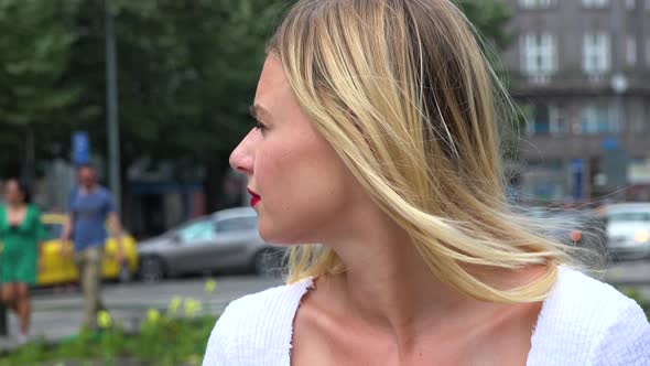 A Young Beautiful Woman Looks Around for Someone in an Urban Area - Face Closeup