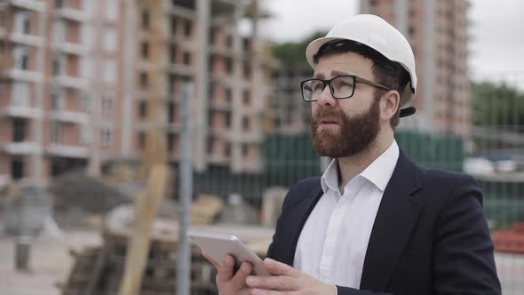 Young Bearded Architect at the Construction Site Taking Photo with Tablet. He Dressed in Business