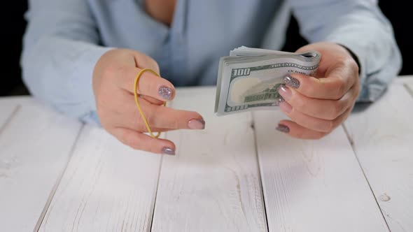 A Woman Tying a Stack of Hundreddollar Bills with a Rubber Band for Money