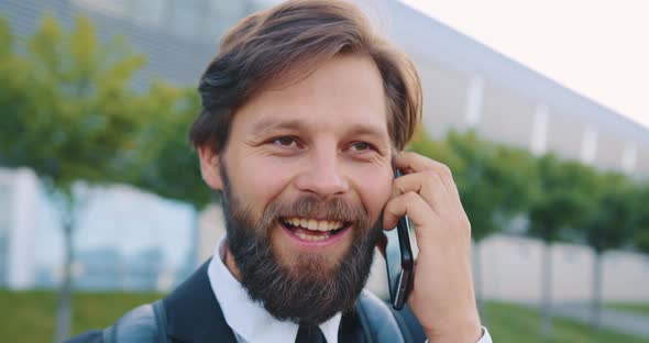 Satisfied Young Man with Well-Groomed Beard which Enjoying His Positive Phone Converstion