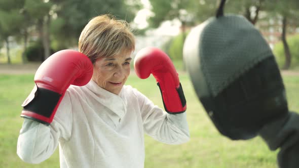 Senior Woman Doing Boxing Workout Training with Personal Trainer Outdoor