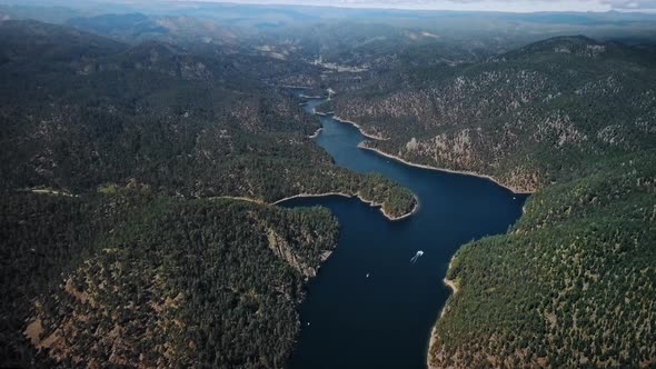 Aerial bird's eye view of Pactola Lake with white boat and wooded hills (Wyoming, USA)